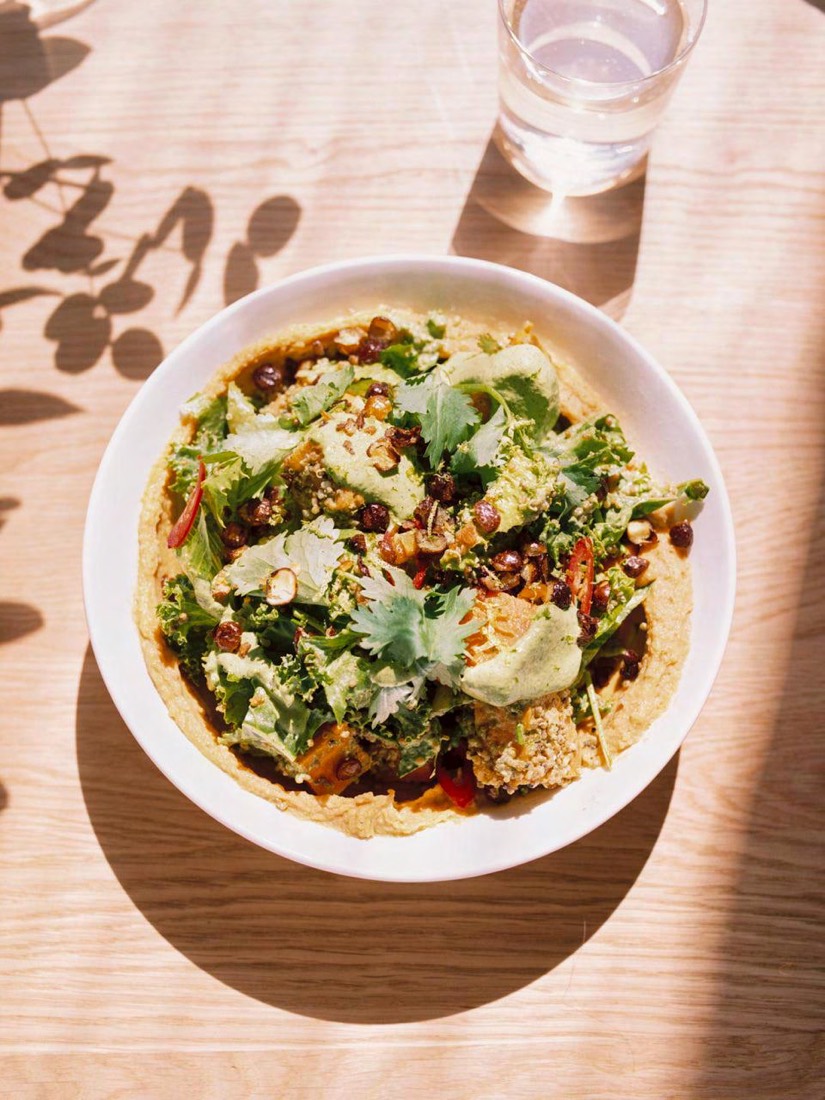 A plant-based bowl topped with herbs, seeds and sauce